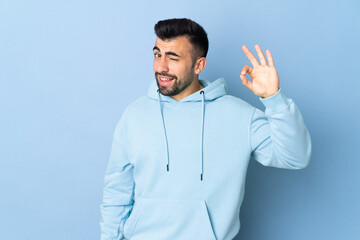 Caucasian man over isolated blue background showing ok sign with fingers