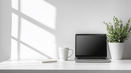 Fototapeta premium A modern, minimalist workspace featuring a laptop, coffee cup, and plant on a white desk.