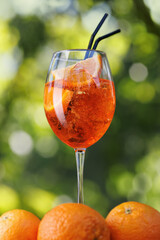 glass of aperol spritz cocktail and ripe orange fruits near outdoors
