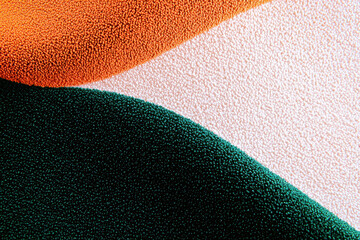 Grainy background. An abstract close-up of textured colorful fabric with smooth curves in orange, green, and cream shades, perfect for artistic and design projects.