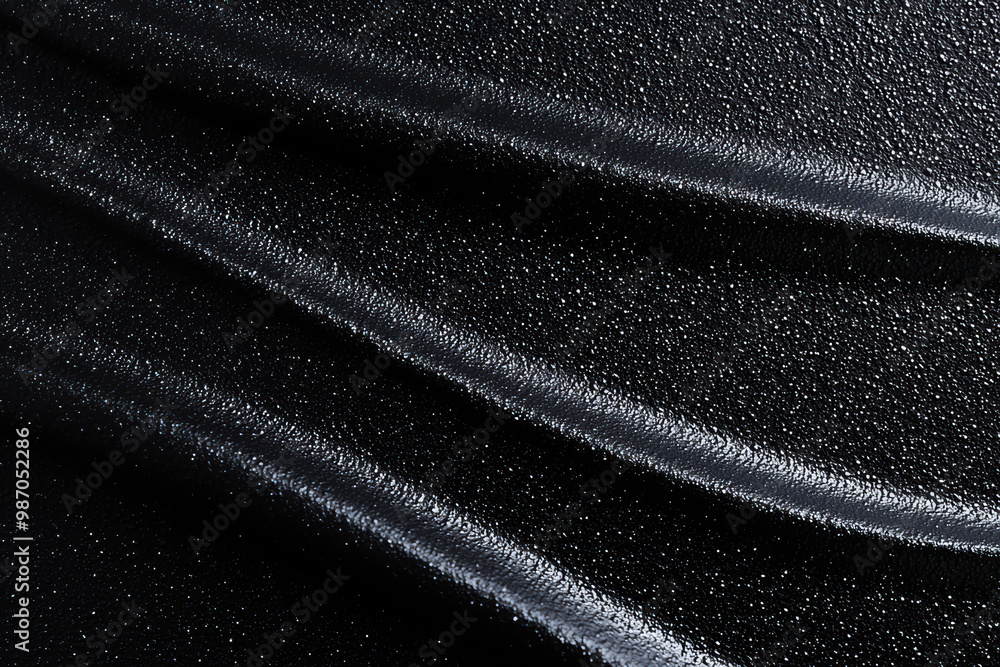 Aufkleber close-up of a textured black surface showcasing elegant curves and a shimmering sheen, ideal for bac