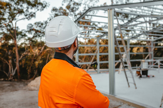 Back view of a man standing in front of a metal structure at the construction site