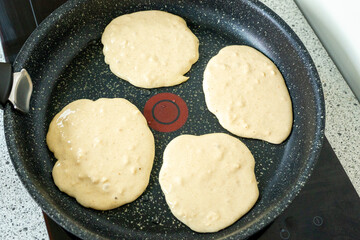 Protein Pancakes Cooking on Non-Stick Pan. Healthy Breakfast in Progress on Speckled Skillet. Four Fluffy Batter Rounds on Dark Granite Cookware