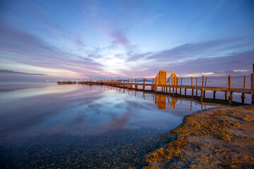 Fototapeta premium Colorful sunrise with the spa wooden walkway in the town of Los Urrutias, Cartagena, Mar Menor, Region of Murcia, Spain