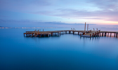 Fototapeta premium Colorful sunrise with the spa wooden walkway in the town of Los Urrutias, Cartagena, Mar Menor, Region of Murcia, Spain