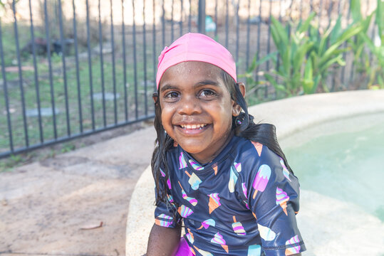 Smiling aboriginal kid sitting by the pool