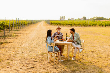 Enjoying a sunny afternoon at a vineyard, friends savor delicious food and wine while sharing laughter and stories