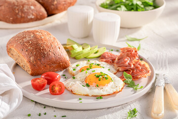 British breakfast with avocado, bun and fied eggs.