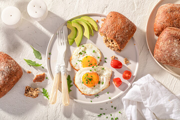 Delicious and crisp breakfast with avocado, bun and fied eggs.