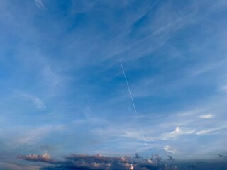 time clouds over blue sky in summer with a fighter jet