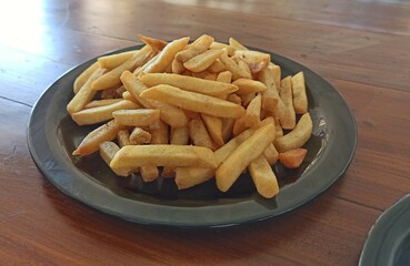 A closeup picture of a french fries served in a black plate