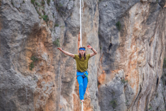 A tightrope walker walks along a cable stretched over a canyon.