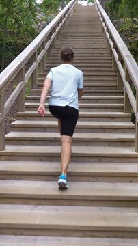 Athletic young woman walking up a Fitness Stairs in a natural park in the woods in Finland.