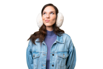 Young caucasian woman wearing winter muffs over isolated background and looking up