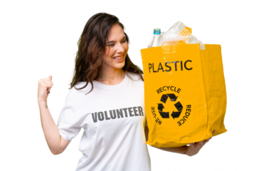Young caucasian woman holding a bag full of plastic bottles to recycle over isolated background celebrating a victory