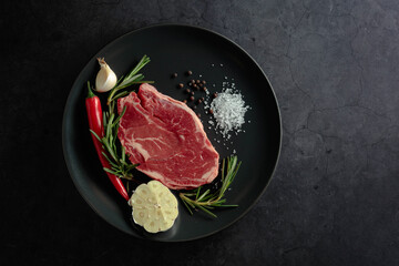 Raw beef meat steak with rosemary, garlic, salt, and pepper.