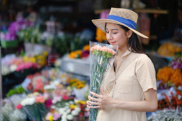 A woman is holding a bouquet of flowers in a flower shop