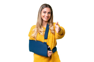 Young Uruguayan woman with broken arm and wearing a sling over isolated background shaking hands...