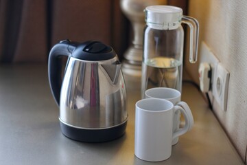 Electric kettle with cups on kitchen table