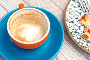 An unfinished cup of cappuccino stands on the table