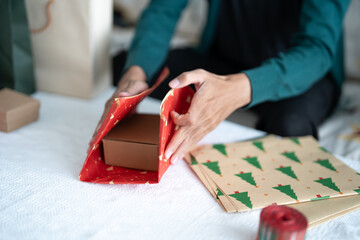 Man in sweater wrapping christmas presents with eco paper girl packing christmas gifts Xmas...