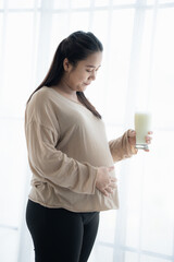 Pregnant asian woman drinking milk at home relaxation and Self-care  Pregnancy drinking a glass of fresh milk mother mindfulness Positive life moment in pregnancy time