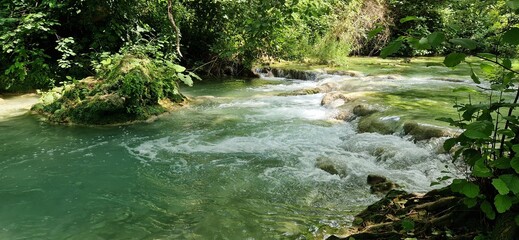 Nice summer sunny day in the Sentierelsa Trail, Colle di Val d'Elsa, Italy. June 26, 2024. Green blue river flows between forest environment.