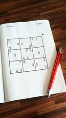 A sudoku game on the table with a pen