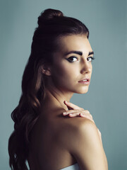 Naklejka premium Makeup, serious and portrait of woman in studio with facial cosmetics routine for glow. Confident, eyeliner and young female person with face for beauty cosmetology isolated by blue background.