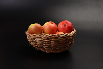 Green yellow red ripe mini pear sweet juicy in basket on wooden table dark background