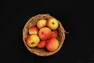 Green yellow red ripe mini pear sweet juicy in basket on wooden table dark background
