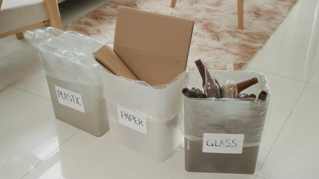 Medium close up shot of three home bins labeled by type of recycling waste