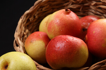 Green yellow red ripe mini pear sweet juicy in basket on wooden table dark background