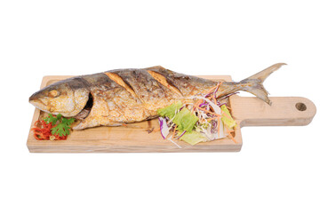 A grilled fish on a wooden cutting board with garnishes of lemon, herbs, and vegetables, isolated on a white background, presenting a meal ready to be served.