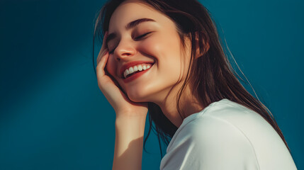 Naklejka premium A joyful woman with a bright smile, holding her face with her hands, posed against a blurred background
