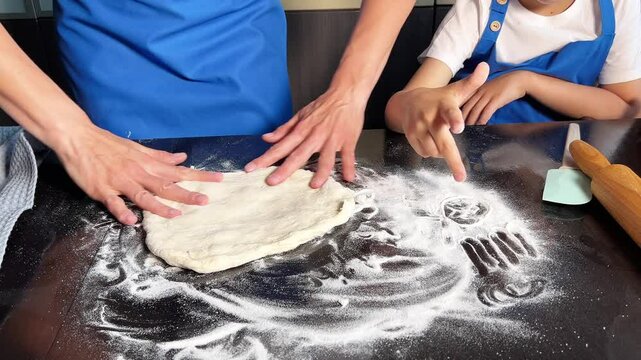 Small boy helping mother prepare dough for baking bread in home kitchen. Homemade bread. Handmade dough. Cooking at home concept. Family concept.