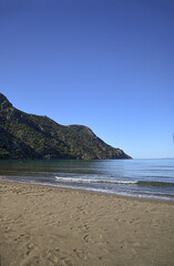 Looking out over the mediterranean from Iztuzu beach in Turkiye. Shallow sandy beach with mountainous headland.