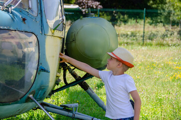 A child stand near an old plane and dreams of becoming a pilot when he grows up. The concept of choosing a future profession. 