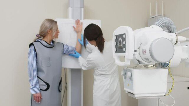 A specialist doctor in an X-ray room, a radiologist sets up a machine for radiography of a patient and makes a scan. The concept of medical technologies, modern medical equipment.
