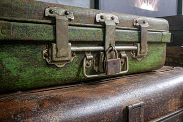 A pile of ancient, rusty suitcases complete with locks and latches that are still locked.