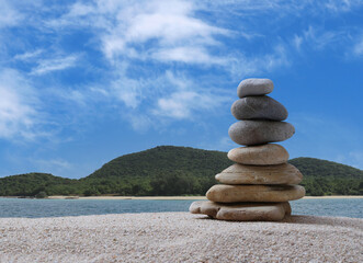 Sandstone are stacked into a pyramid shape on sea and cloud background and copy space.