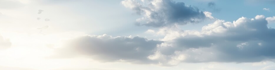 Obraz premium A serene sky filled with soft clouds, illuminated by bright sunlight, evokes a sense of calm and tranquility.