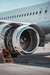 Airplane engine maintenance. White passenger aircraft on airport apron with opened cowl doors for...