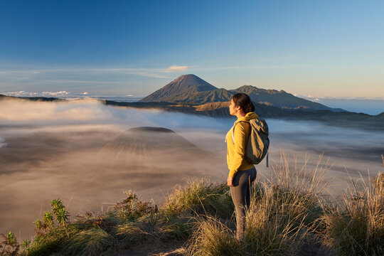 Asia, Indonesia, Java, Bromo Semeru national park, mature female tourist trekking at mount Bromo at sunrise, standing at viewpoint admiring view

