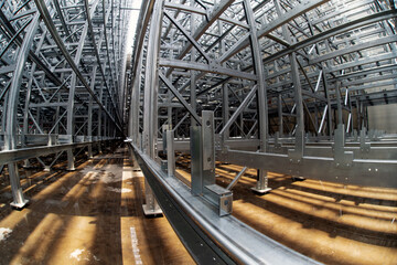 Fish-eye view of steel galvanised framework clad rack structure of asrs warehouse with sprinkler system piping and reflections in rainwater pond