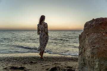 Woman Beach Sunset - Silhouetted woman stands on the beach at sunset, gazing out at the ocean.