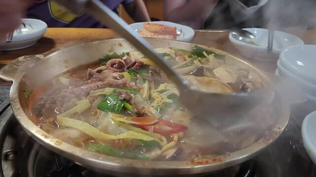 펄펄 끓는 낚지 전골을 국자로 뒤적이면서 끓여 내는 