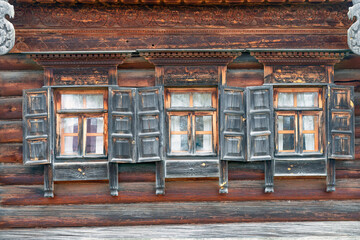 Windows of a wooden house with wooden carved architraves and shutters