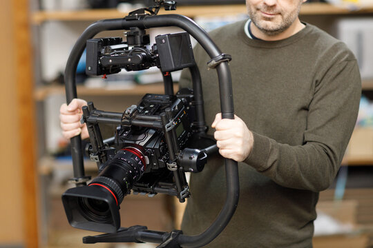 Professional videographer holding camera on gimbal rig steadycam to make video without shaking