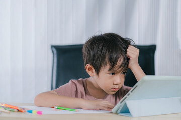 Naklejka premium Depressed little boy with tablet,asian child boy learning online on tablet digital at home.
